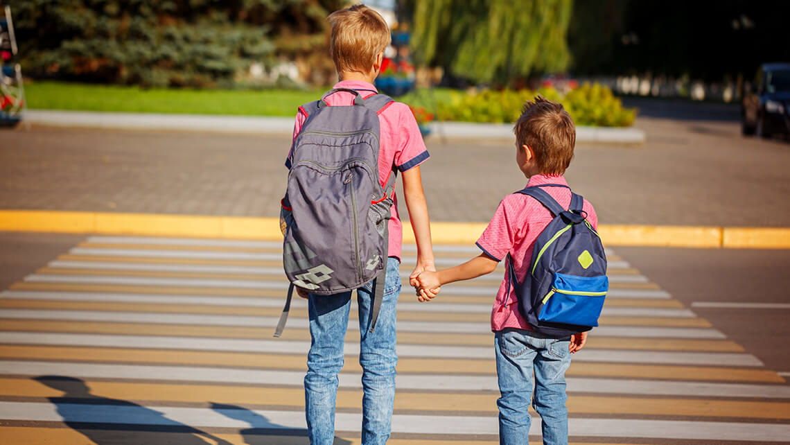 two boys holding ands before crossing the street