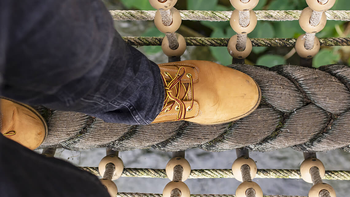 close-up person walking on rope bridge